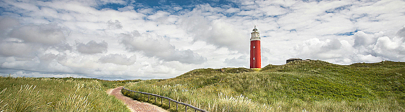 Grüner Deich mit blauem Himmel, Wolken und Leuchtturm