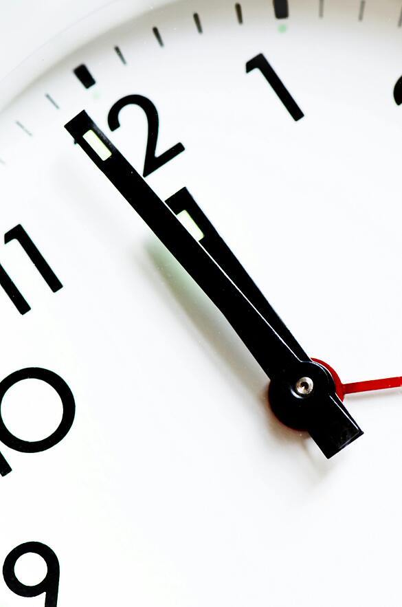 Weißes Zifferblatt einer Uhr mit schwarzen Ziffern und Zeigern