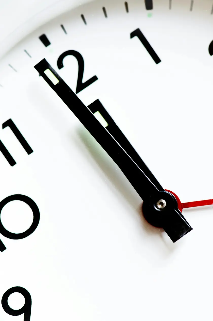 Weißes Zifferblatt einer Uhr mit schwarzen Ziffern und Zeigern